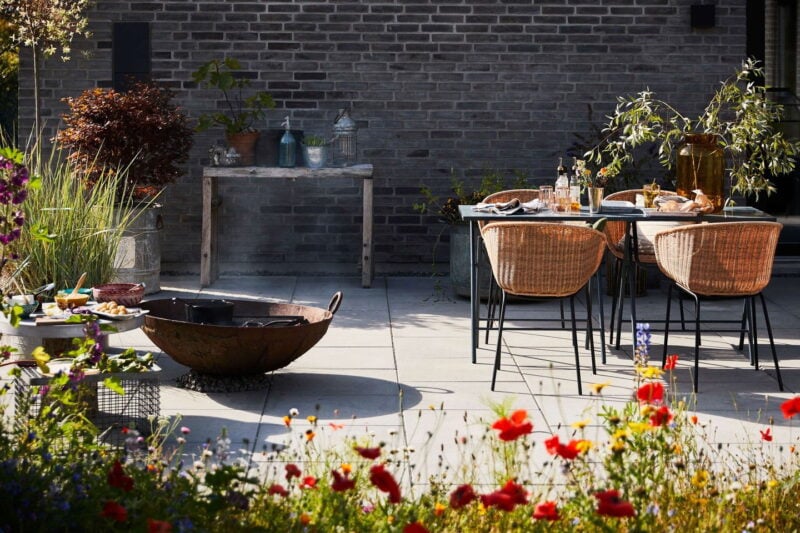 Terrasse med store fliser, bålfad og havemøbler